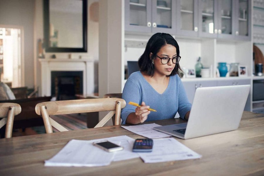 Young woman using a laptop at a kitchen table while working from home