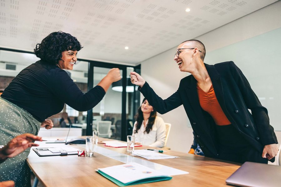Smiling businesswomen fist bumping each other before a meeting in a boardroom