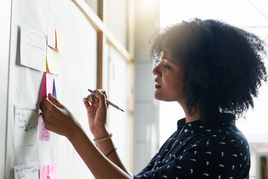 A young female designer working with sticky notes on a board