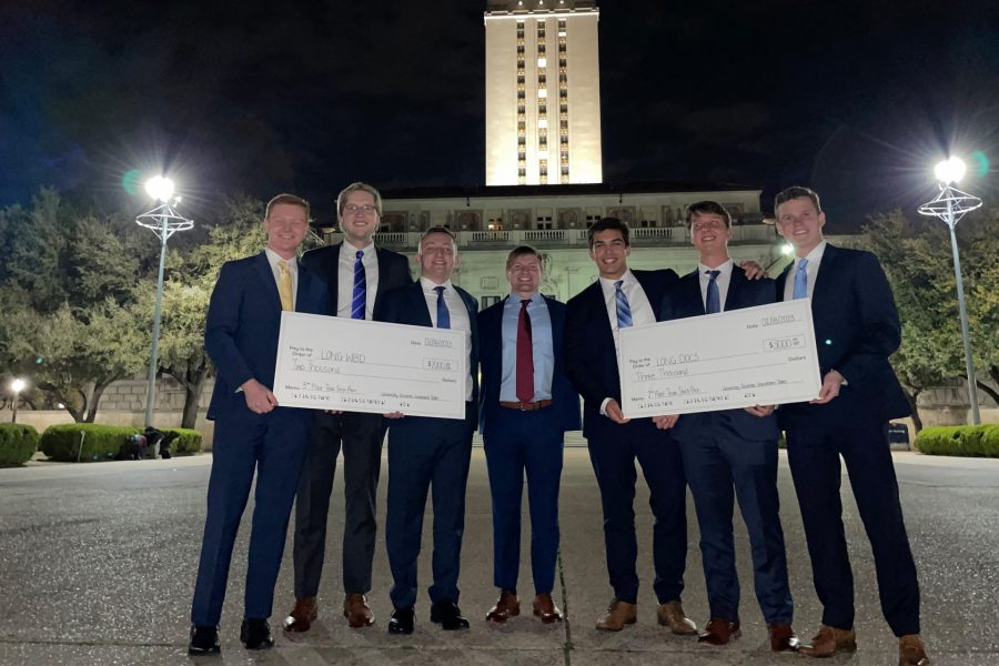 Students hold two giant checks won at a competition.
