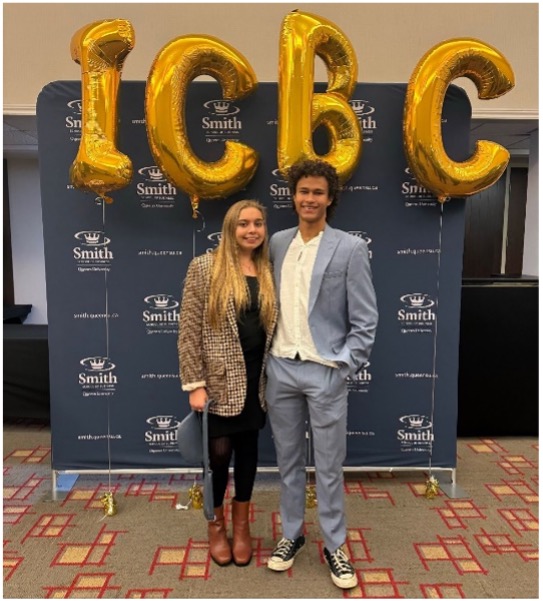 Two students pose with balloons.