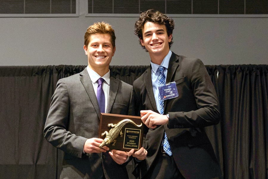 Two students in suits smile while holding a plaque awarded for winning the 2025 Student Challenge at the Future Advisor Conference.