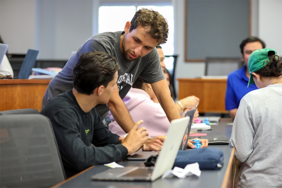 Two students engage in a focused discussion during a peer mentoring session in a classroom setting.