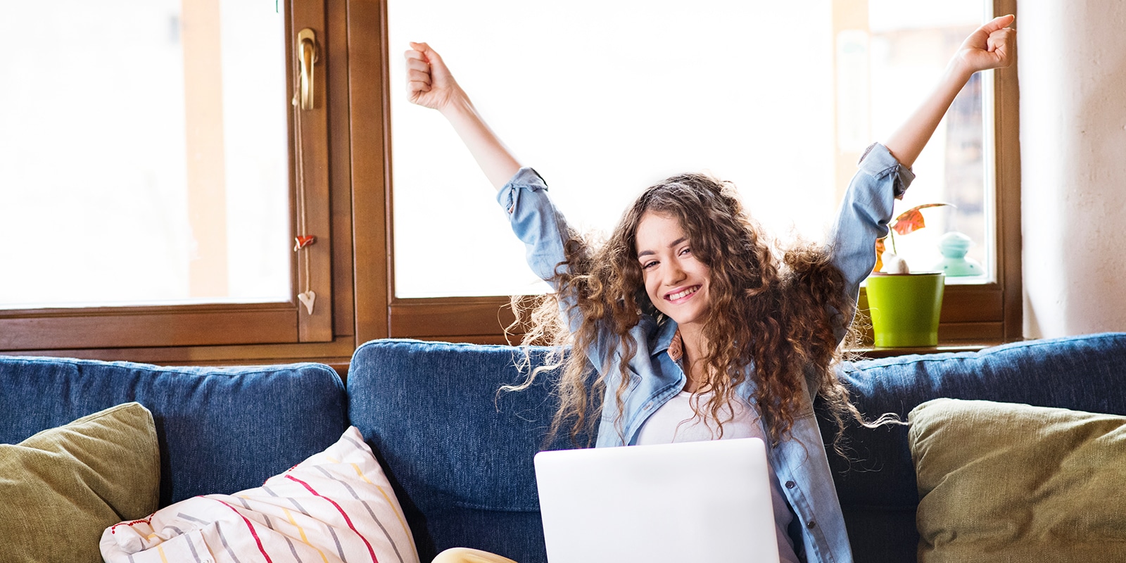 A prospective student interested in the University of Florida Warrington College of Business raises their arms after completing their application on their laptop