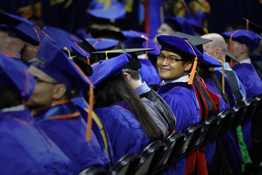 A row of doctoral students from the University of Florida Warrington College of Business in caps and gowns during commencement
