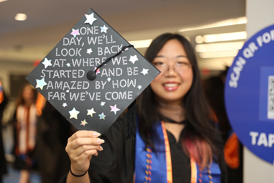 A graduate student from the University of Florida Warrington College of Business holds up a graduation cap featuring a message spelled out in stars and rhinestones