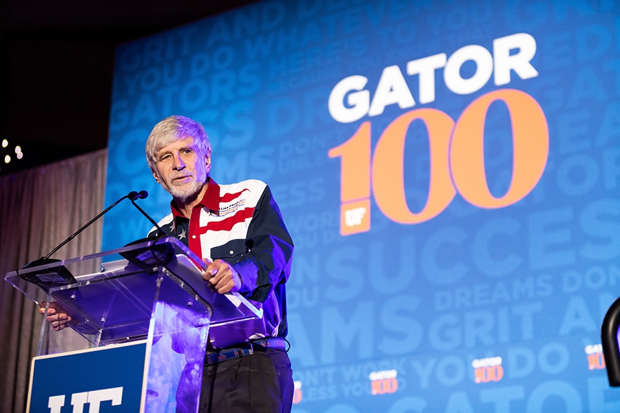 A alum on the University of Florida Gator100 list stands behind a podium to discuss his accomplishments