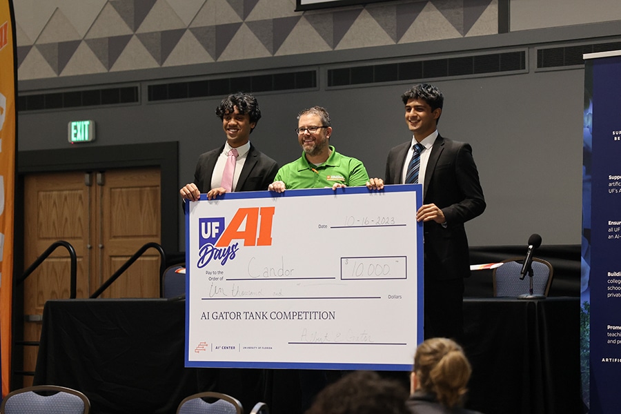 Three combination degree students from the University of Florida Warrington College of Business pose with the check they earned after winning the AI Gator Tank entrepreneurship competition