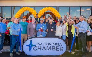A large group of people stand in front of a McDonald's restaurant during a ribbon cutting ceremony. A "Wilton Area Chamber" sign is place in front of them.