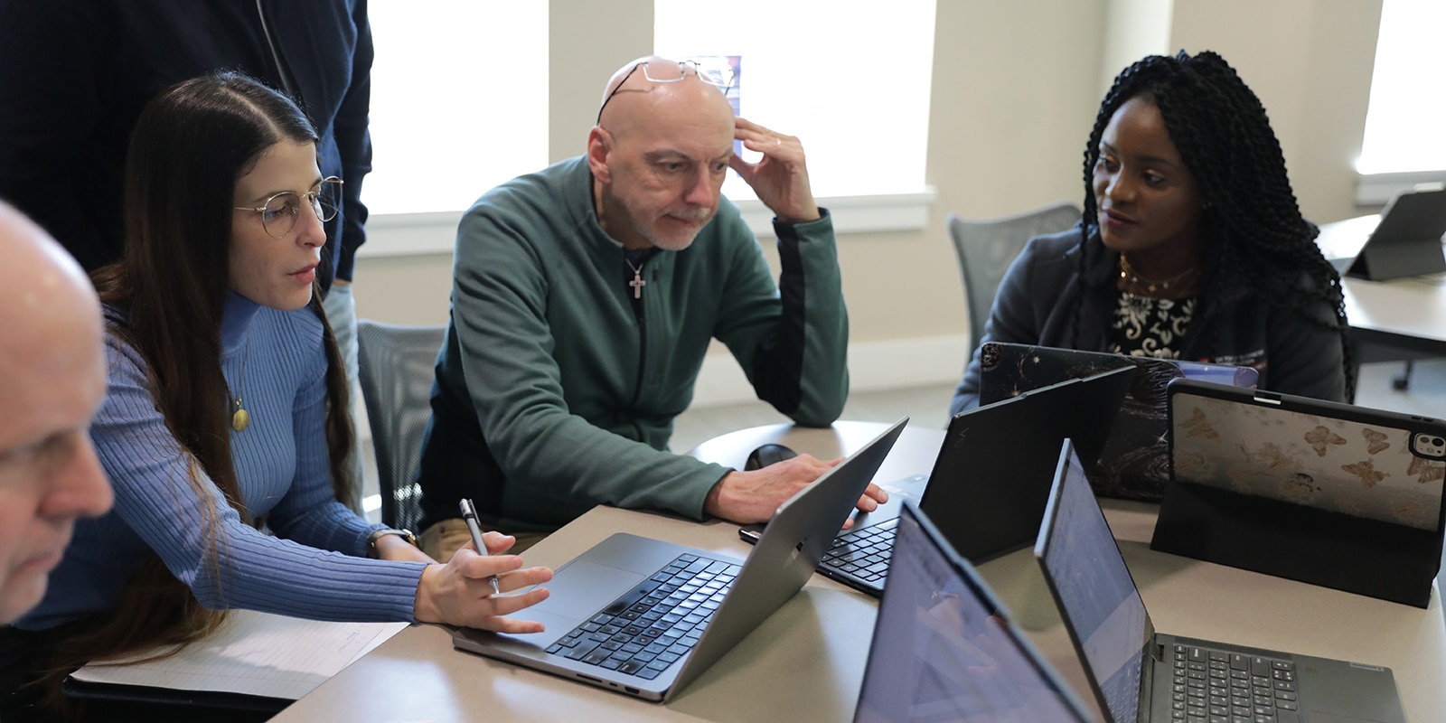 In a group with their laptops out, UF Warrington DBA students meet to discuss their research projects