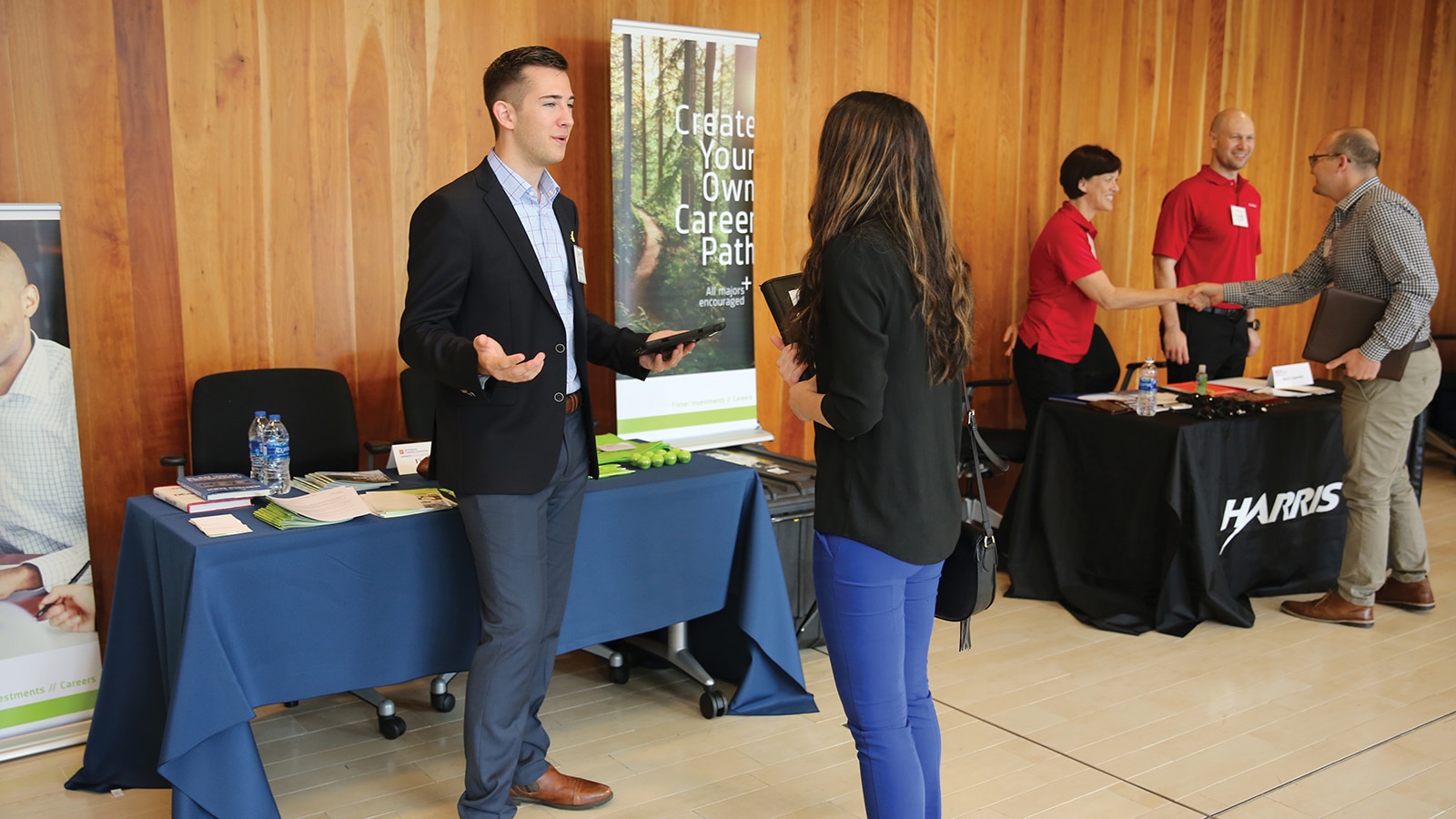 A University of Florida Warrington College of Business student speaks with a recruiter during a job fair, with a sign reading Create Your Own Career Path in the background