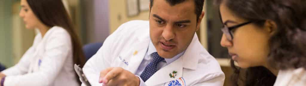 Wearing lab coats, two joint/MBA students from the University of Florida Warrington College of Business examine samples closely