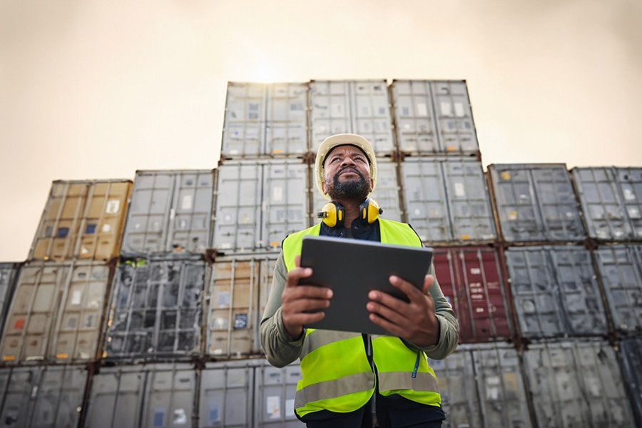 During a practicum assignment at a shipping port, a University of Florida Warrington College of Business MBA/MS in Information Systems and Operations Management student holds a tablet and wears a hi-vis vest