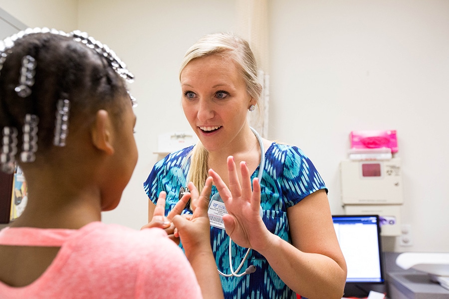 A student enrolled in the University of Florida Warrington College of Business' joint MD/MBA program engages with a young patient during a clinical assignment