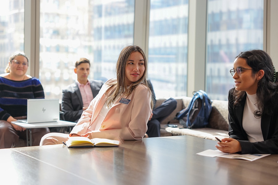 UF Warrington College of Business students enrolled in the joint MBA/MS in Information Systems and Operations Management program take notes with notebooks or laptops in a classroom with windows