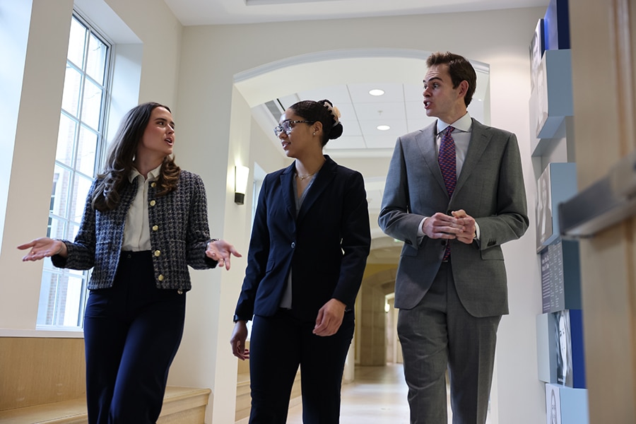 Three students enrolled in the UF Warrington College of Business' joint MD/MS in Management program converse while walking along a hallway