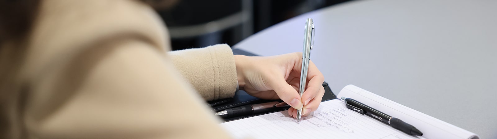 A student writes on a pad with a pen in a class for the University of Florida Warrington College of Business' MSM program