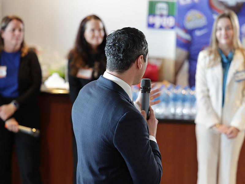 Photo of a man speaking in a microphone. 