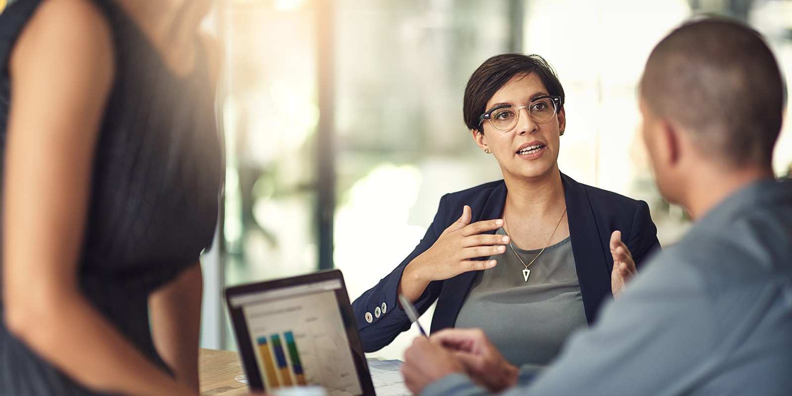 A UF Master of Accounting student with graphs pulled up on a tablet listens to an instructor sitting behind a table explain a related concept