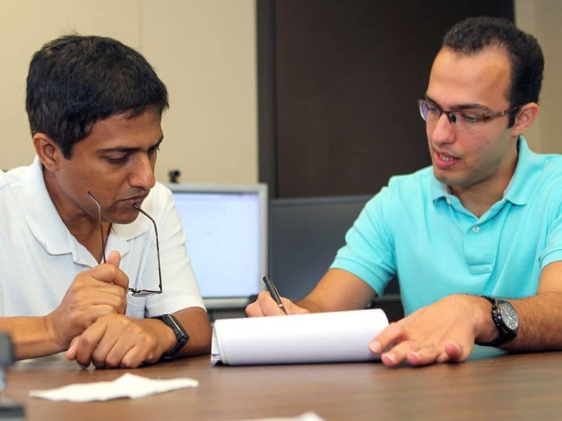 Sitting behind a table, two researchers from UF Warrington's International Accounting and Auditing Center review data written on a pad of paper