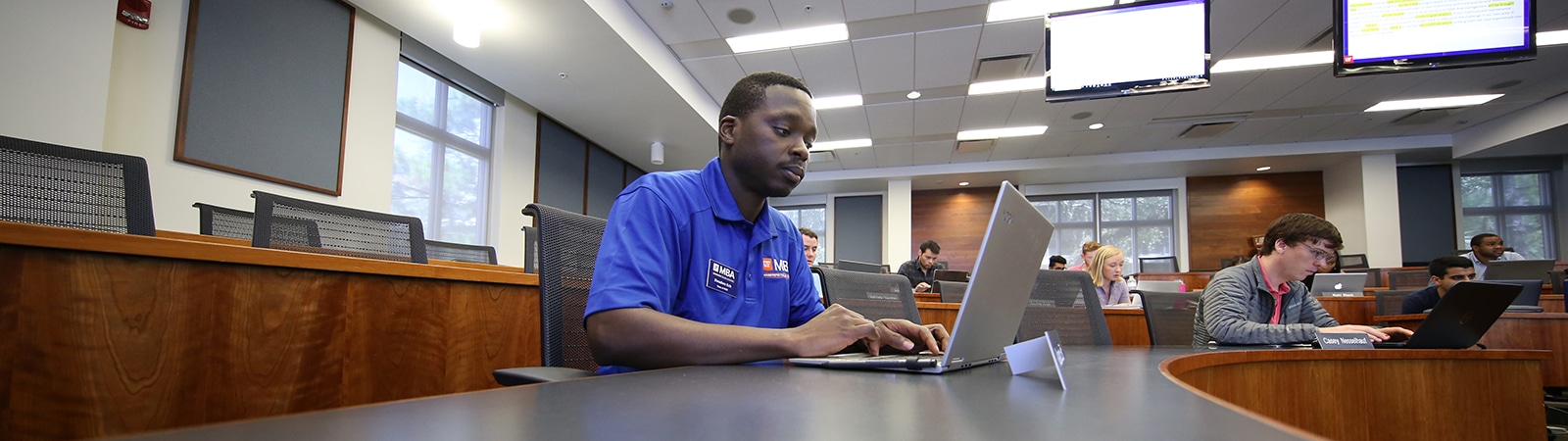 A student from a University of Florida Warrington College of Business MBA program types on a laptop in a classroom