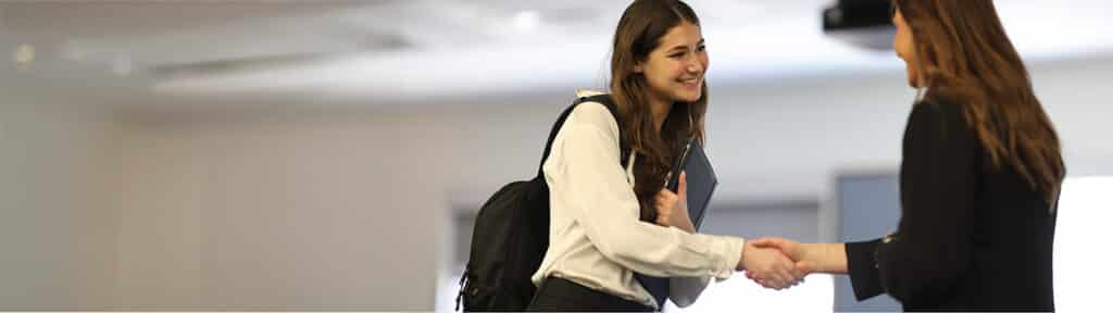 A current University of Florida Warrington College of Business student smiles and shakes hands with a prospective employer