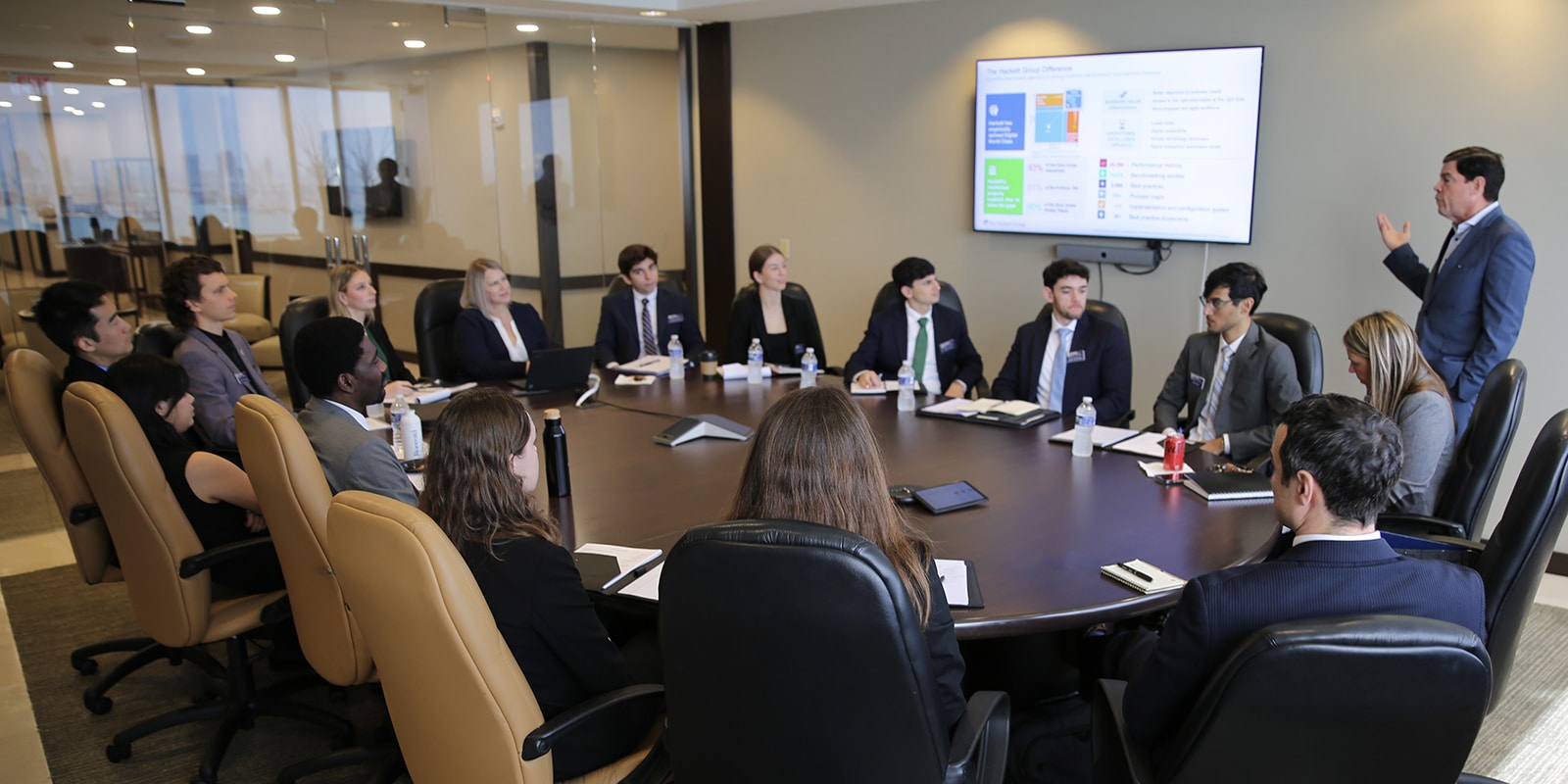 An industry partner makes a presentation, using slides, to a room of University of Florida Warrington College of Business students sitting around a table