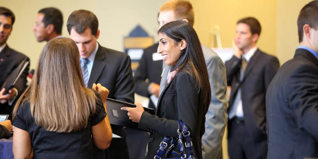 Students from the University of Florida's MBA programs, wearing suits, talk with recruiters during a career event