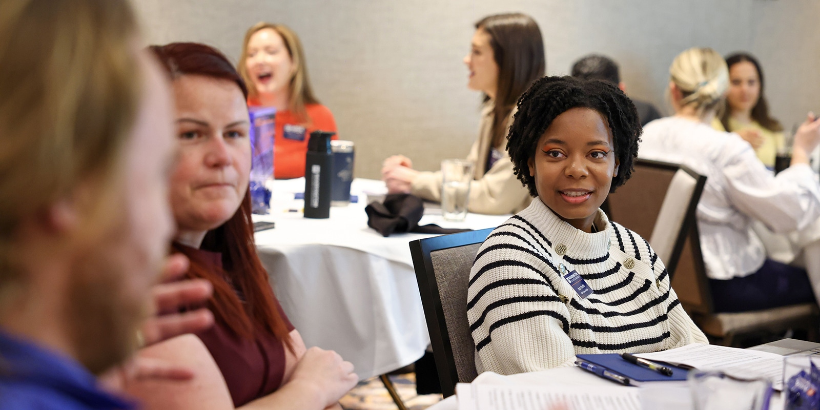 UF Warrington MBA students with notebooks and brochures converse while sitting around a table during a Summit Series event