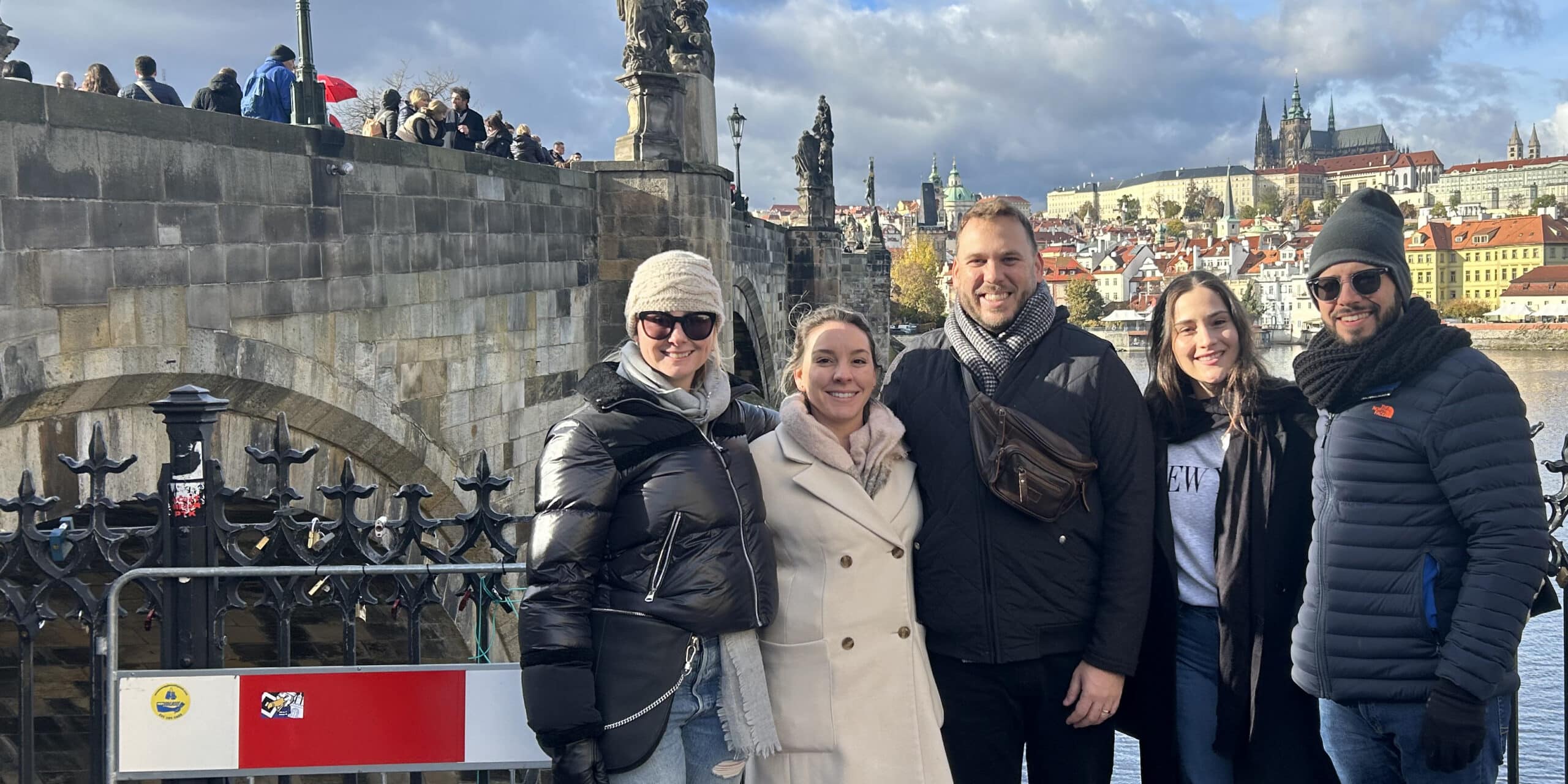 A University of Florida Warrington College of Business student on a study abroad trip stands smiling in front of a historic stone aqueduct, pointing to the structure, with a scenic view in the background.