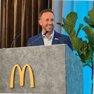 David Costa stands at a podium with a large McDonald's M on the front.