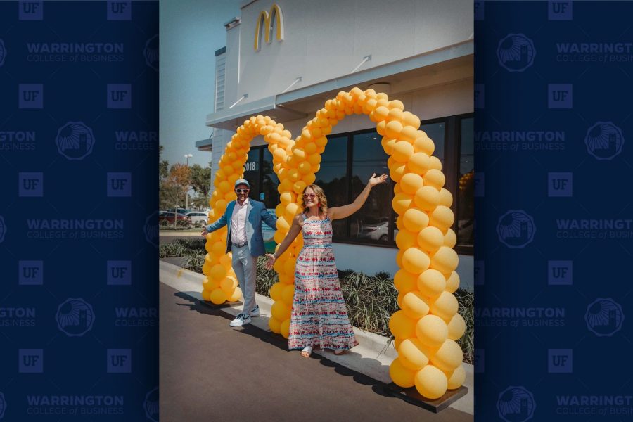 David Costa and his wife pose in front of a McDonald's M balloon arch at the opening of one of their store locations.