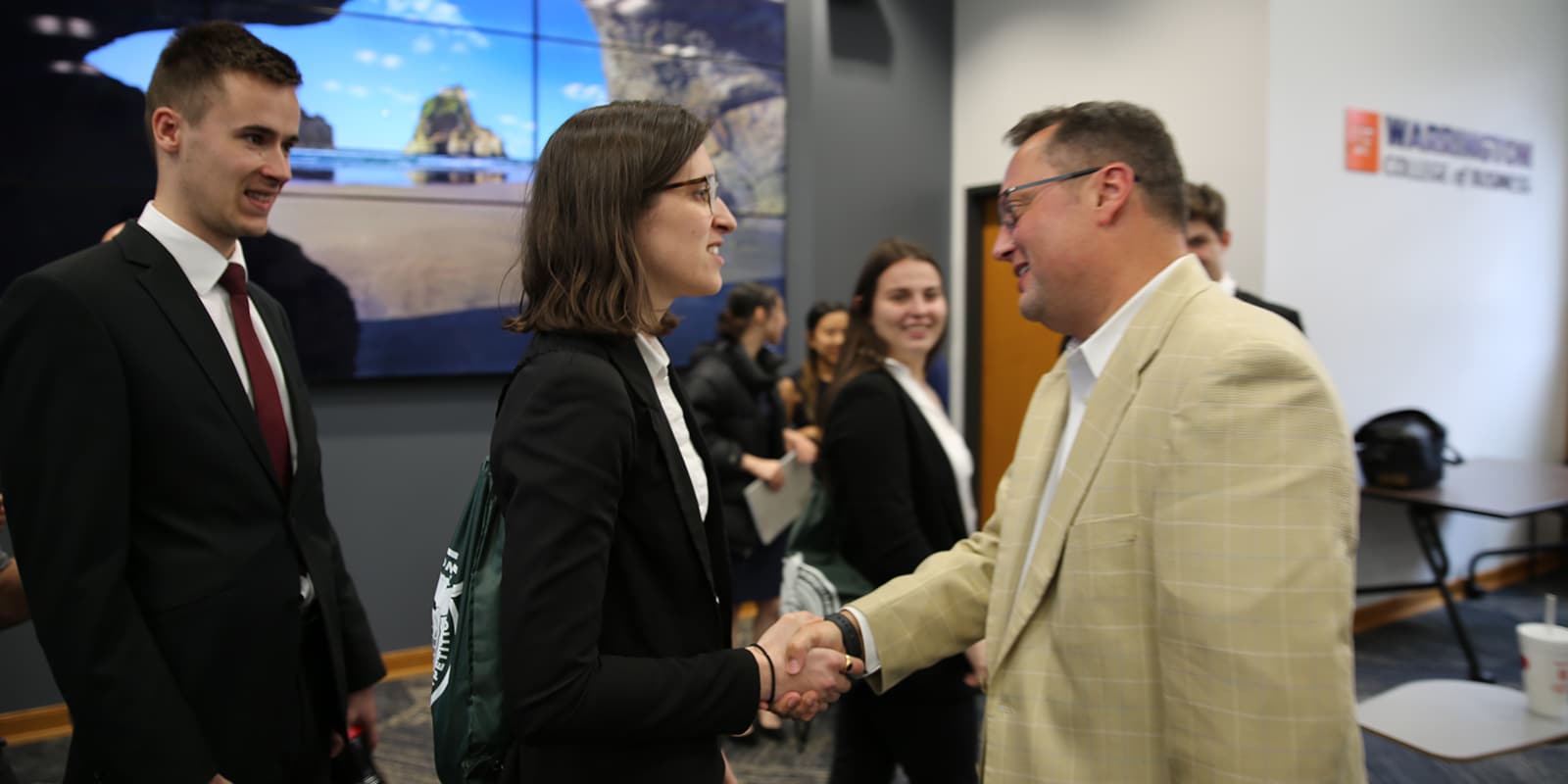 A female student shaking hands with a male recruiter. 