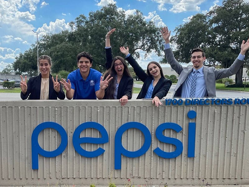 Ariella Ciuraru and other interns posing with a Pepsi sign.