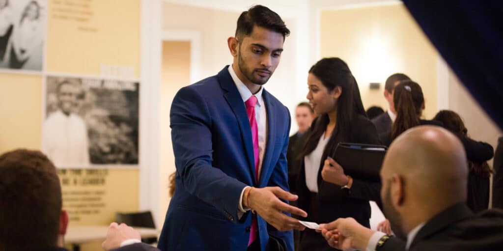 A BABA student takes a business card from a recruiter during a career and internship fair held by the UF Warrington College of Business