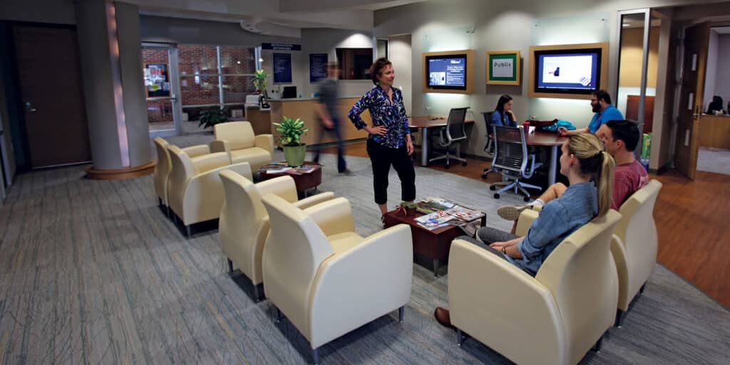 BSBA in Management and faculty have a conversation in a common area for UF Warrington's Miller Retail Center