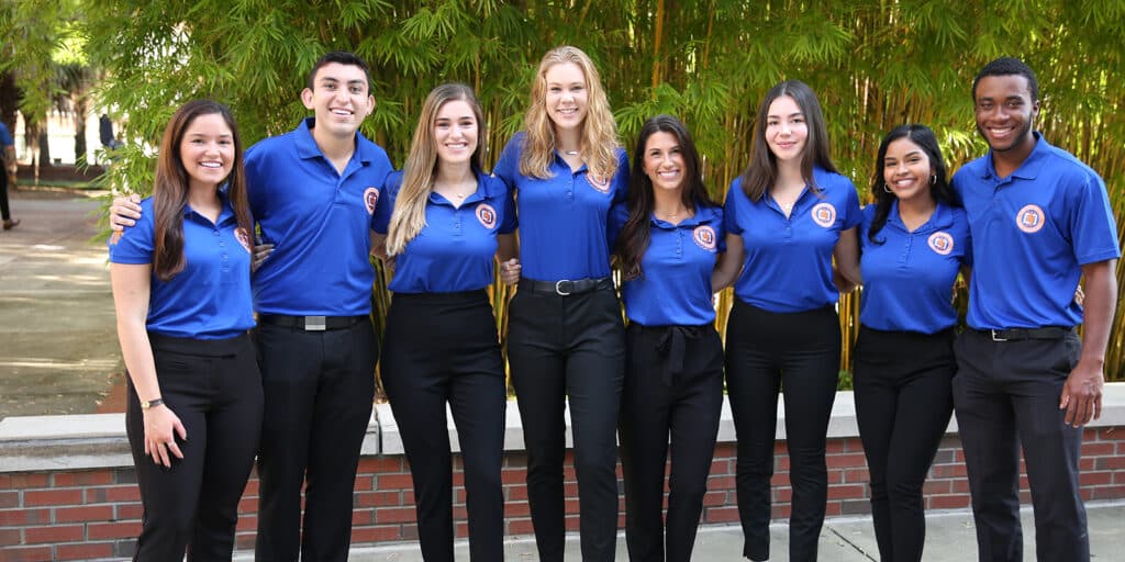 The Warrington Diplomats, including BSBA in Management students, lock arms as they stand in a row