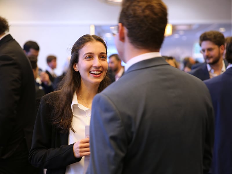 A smiling woman in a business suit conversing with a man in a suit at the Fisher School of Accounting's Spring Banquet.