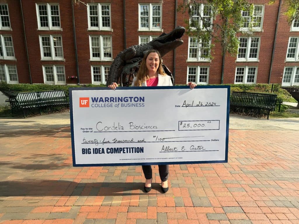 Cordelia Biosciences representative holding an oversized check for $25,000 from the Big Idea Competition. 