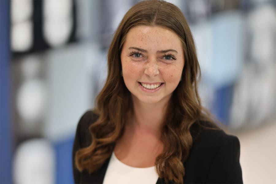 Danielle Reid, VP of Marketing and Public Relations for Business Ethics Ambassadors, smiles in a professional headshot, wearing a black blazer over a white top, with wavy brown hair.