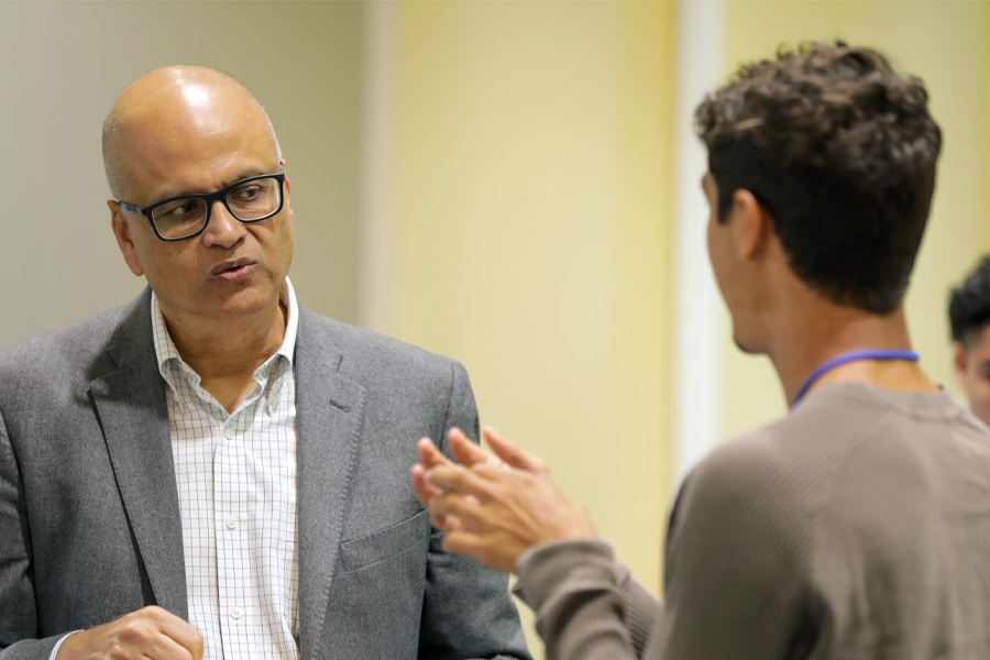 Saby Mitra, Dean of Warrington College of Business, engaged in a conversation with a student in a professional setting.