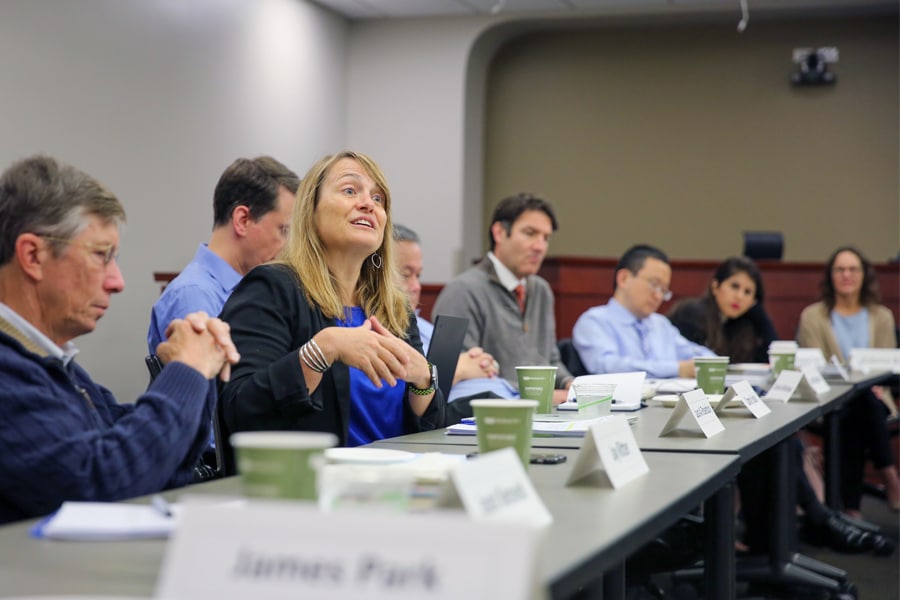 A group of professionals sit around a conference table, listening and sharing insights during a leadership advisory meeting at PURC.