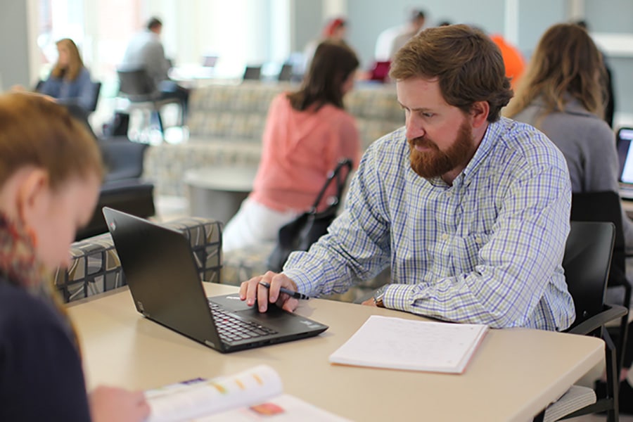 A man sitting at a table with his laptop and notebook.