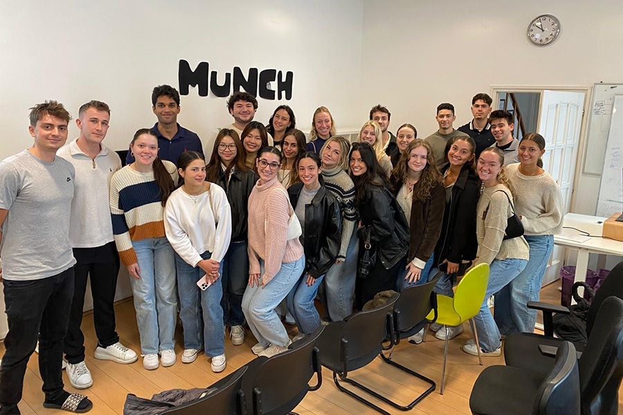 A group of students posed in front of the Munch logo. 