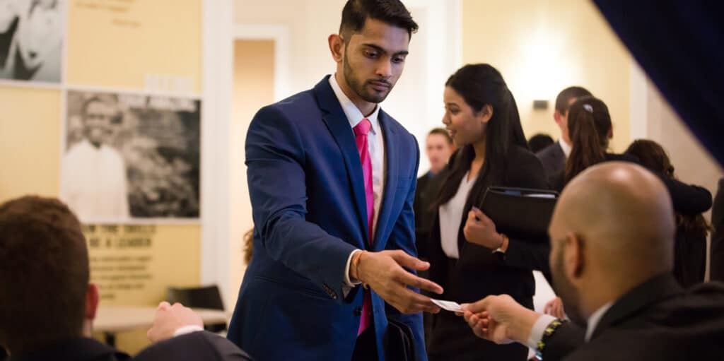 A student from UF Warrington's Online BABA program takes a business card from a recruiter at a job fair