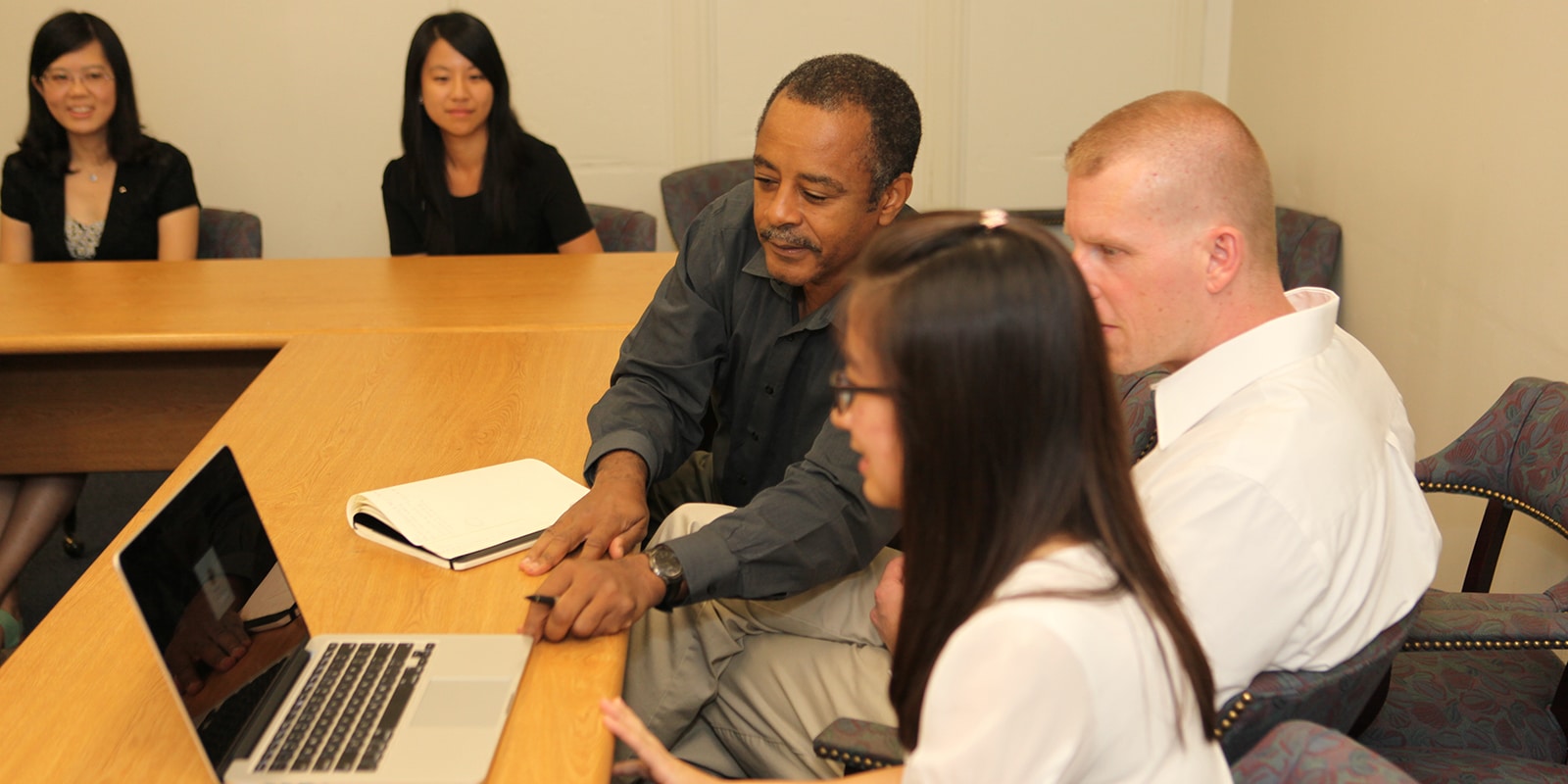 Faculty, PhD in Management. and more students around a table during a meeting for the University of Florida's Business Ethics Center