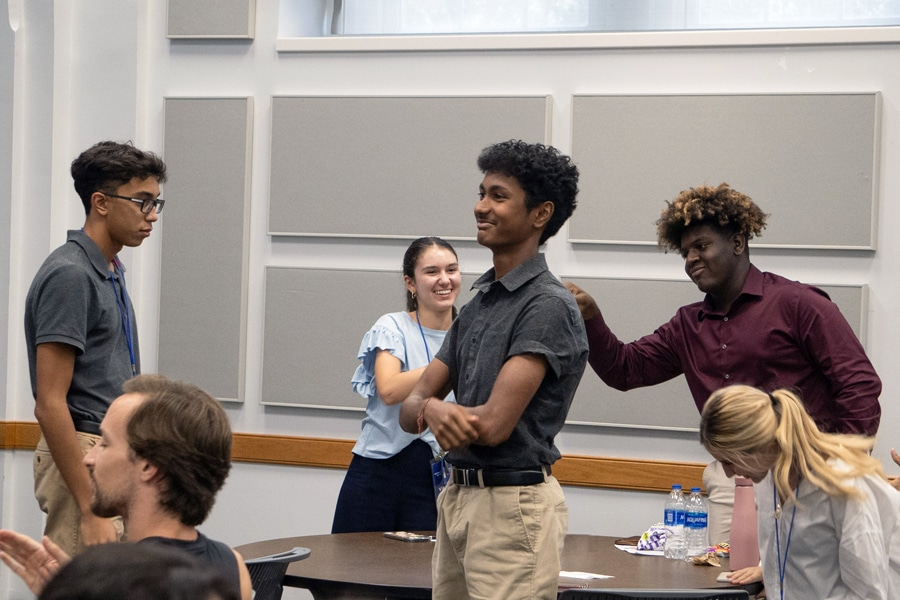 A group of diverse college students stand and chat in a classroom, smiling and engaging with each other during an event.
