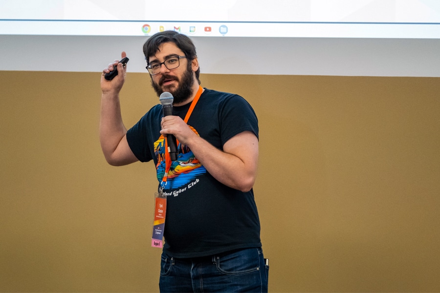 A man speaking in front of a presentation. 