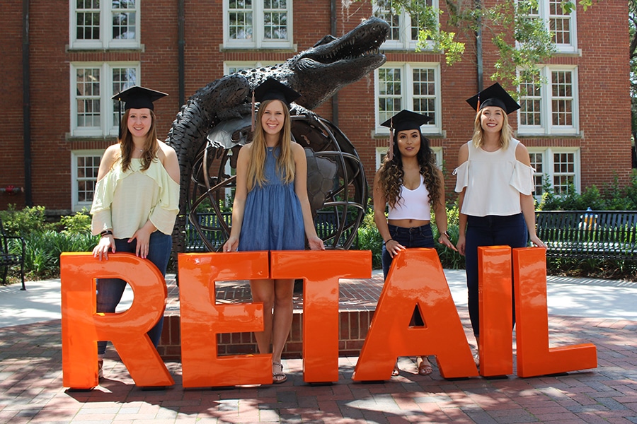 Retail grads in front of larger letters spelling R-E-T-A-I-L.