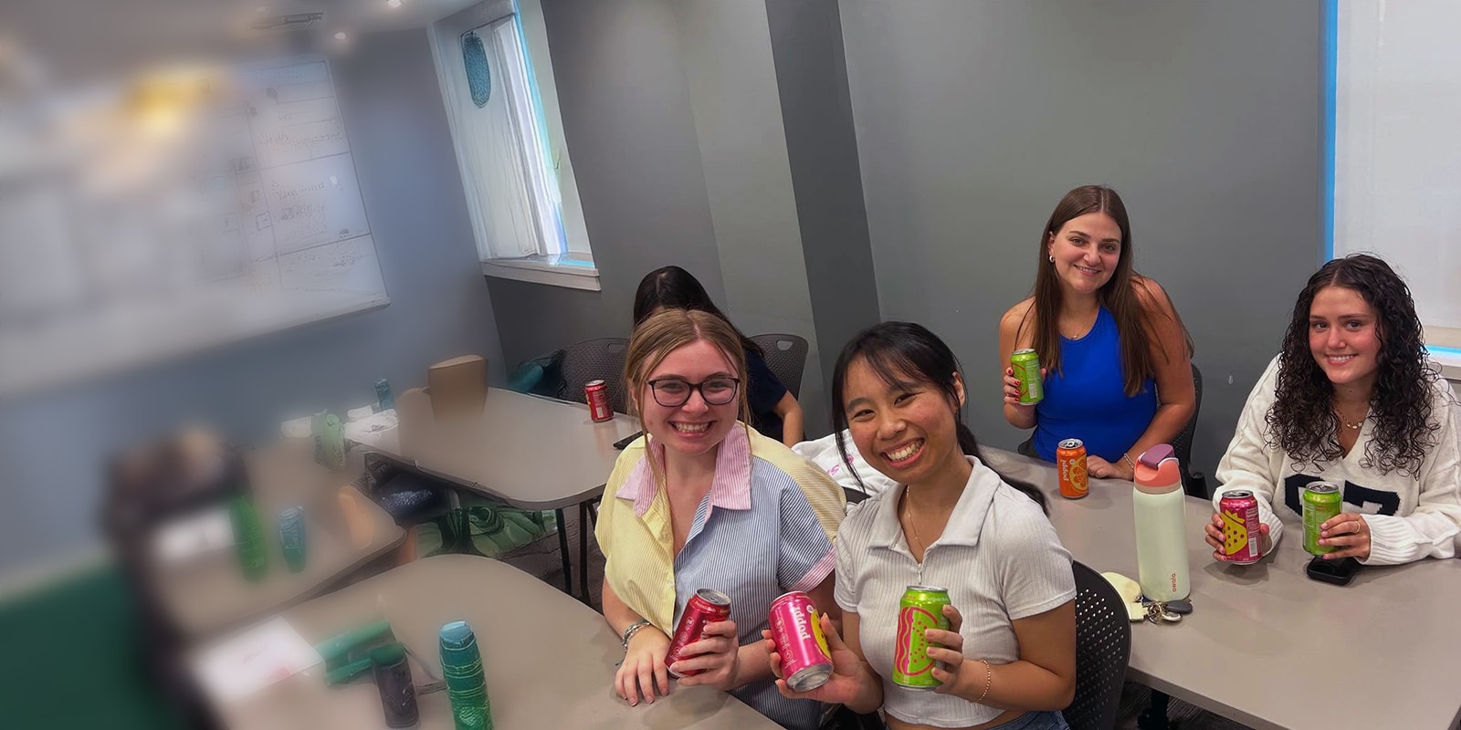 Four female students pose with Poppi beverages.